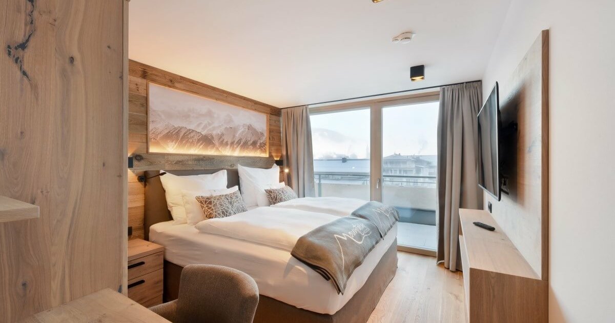 Doppelzimmer mit großem Bett mit weißer Bettwäsche im Penthouse in Kaprun