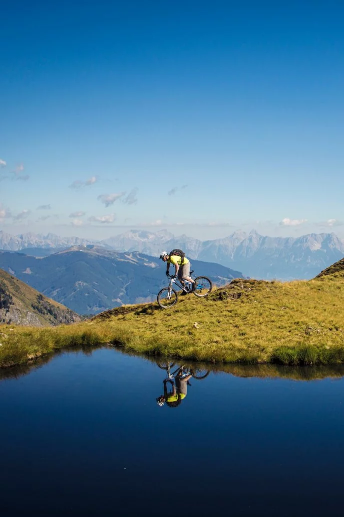 Ein Mountainbiker auf einem Berg neben einem Bergsee bei sonnigem Wetter