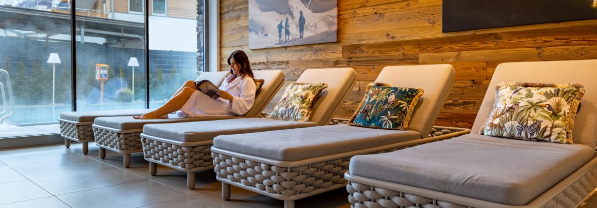 Dame auf einer Liege im Spa-Bereich beim Lesen