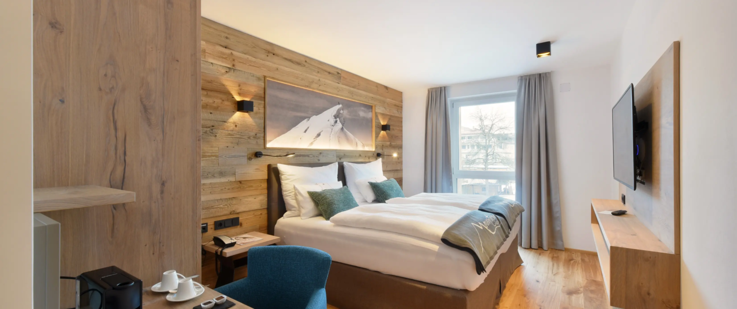 Modernes Hotelzimmer mit Doppelbett, Holzdesign und warmem Licht