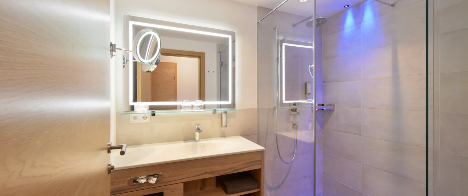 Modernes Badezimmer mit Dusche, Waschbecken und Spiegelbeleuchtung